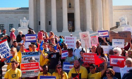 Protesters hold up anti-gerrymandering signs.