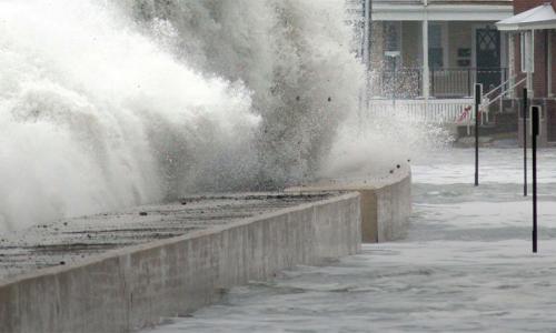 wave breaking on sea wall flooding neighborhood