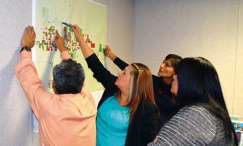 A group of people working at a map hanging on a wall